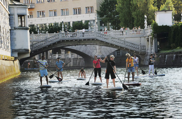 Ljubljana: eden najlepših načinov, kako izkusiti prestolnico, je prav iz vodne perspektive. Skupina suparjev na Ljubljanici pri Tromostovju.