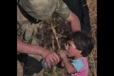 Turški vojak daje vodo sirijskemu otroku