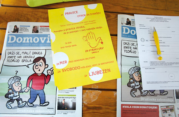 Pozor, otroke je treba zavarovati pred krivoverskimi nauki (fotografije naslovnice Domovine na stojnici, kjer zbirajo podpise za razpis referenduma)