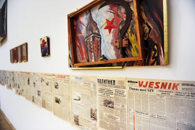 Okrog razstavljenih umetnin se vije kača iz naslovnic glavnih jugoslovanskih časnikov s konca osemdesetih in tako izziva takratni in današnji politični kontekst.