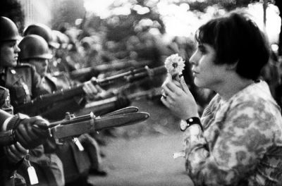 Mlada ameriška mirovnica je med pohodom na Pentagon stopila pred bajonete v znak protesta proti vojni v Vietnamu; Washington, leta 1967.