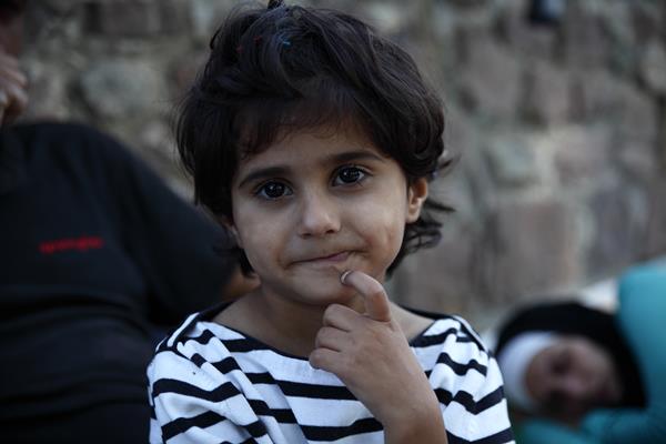 Deklica je uživala pred fotografskim objektivom, medtem, ko je njena mati počivala po naporni poti v begunsko taborišče