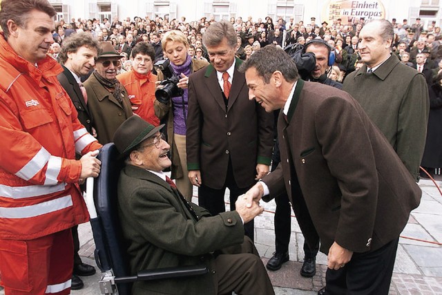 Jorg Haider se rokuje z veteranom Ernstom Tischlerjem. Desno je avstrijski predsednik Thomas Klestil