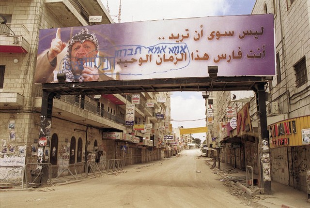 Plakat s palestinskim voditeljem Jaserjem Arafatom, kljub izraelskim vojakom, še vedno visi v središču prazne Ramale.