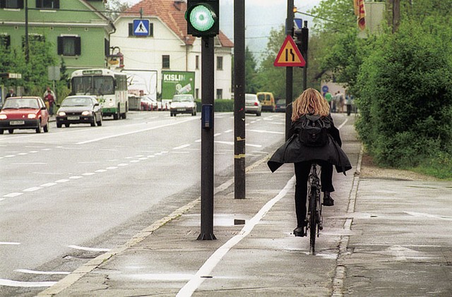 Kolesarska steza na Ježici je narisana kar 'skozi' drogove za signalizacijo in razsvetljavo. Spet enaka filozofija: kolesar se bo že znašel. Da ne bo pomote - kolesarka na fotografiji se vozi po površini za pešce, kolesarska steza je na njeni levi!