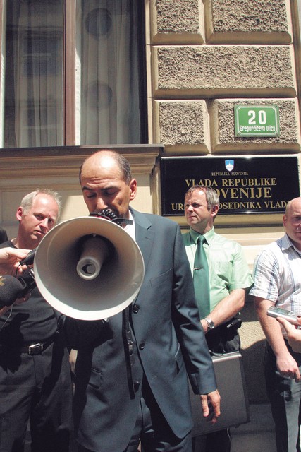Začetek: protest prebivalcev Dolenjske proti Romom pred parlametom 27. maja 2004. Govornik Janez Janša, levo za njim Silvo Mesojedec, kandidat SDS na volitvah, desno za njim Ivan Grill, tudi kandidat SDS na volitvah