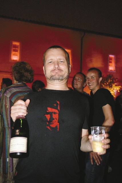 Paul Lowe, nekdanji Magnumov fotograf, sedaj član agencije Panos, proslavlja s šampanjcem in podobo Tita na majici.