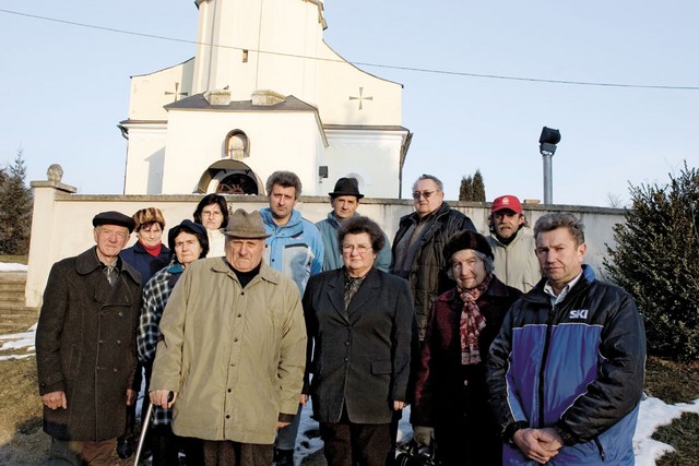 Člani cerkvenega pevskega zbora so se pred obnovljeno cerkvijo v Sromljah zbrali v podporo svojemu župniku.