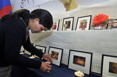 Borka za pravice Tibeta prižiga svečke pred fotografijami Tibetancev, za katere mislijo, da so jih ubili v Tibetu od marca lani. Na žrtve so se spomnili na prvi dan tibetanskega novega leta v samostanu Namgyal v indijski Dharmsali.
