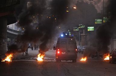 Prebijanje dostavnih vozil mimo gorečih barikad med protivladnimi protesti v Kairu.