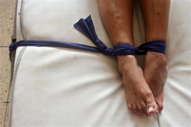 Bolnica, privezana za posteljo na ženskem oddelku psihiatrične bolnišnice v Managui, Nikaragva. WHO opozarja, da se skrb za bolnike v revnejših državah zaradi svetovne gospodarske krize nedopustno znižuje