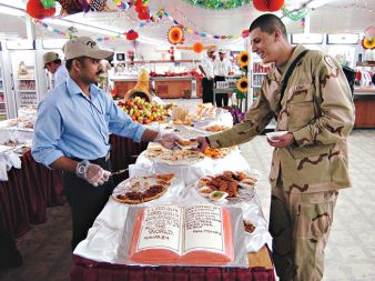 Uslužbenec podjetja Halliburton/KBR, Gopi Krishna naredniku Miguelu Gallegosu servira kos bučne pite ob ameriškem prazniku Dan zahvalnosti, 25. novembra 2004 v iraški zračni bazi v Kirkuku.