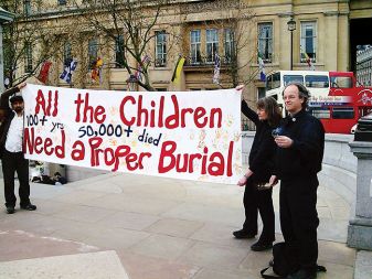 Kevin Annett (desno) pred kandasko ambasado v Londonu 12. aprila 2010. Napis na transparentu: „Vsi otroci, njih 50.000 in več, si zaslužijo dostojanstven pokop.“