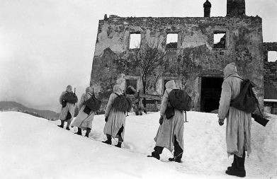 Partizanska izvidnica Notranjskega odreda na poti mimo ruševin v Loški dolini 1945.