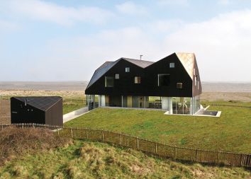 Dune House je odlična reinvencija in reinterpretacija angleške obalne stanovanjske gradnje. Stavba ima kompleksno geometrijo strehe, ki je referenčna za obalne stavbe, a vendar je oblikovana prepoznavno in sodobno. Jarmund/Vigsnæs Architects so v zgornjem nadstropju želeli oblikovati več kot le prostore za spanje. Zato ima vsaka od štirih sob tudi kopalno kad, ob kateri je okno, tako da lahko tisti, ki se namaka, hkrati opazuje Severno morje in okoliške travnike. V zgornjem nadstropju so še ločena kopalnica in stranišče ob vsaki sobi, manjša knjižnica ter terasa na strehi.