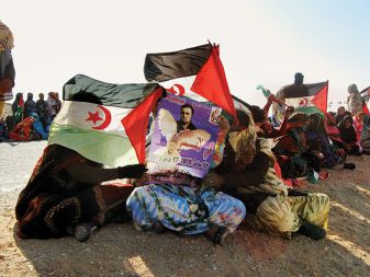 Sahravijske begunke v taborišču Smara v Alžiriji med manifestacijo v podporo neodvisnosti Zahodne Sahare; dve tretjini njenega ozemlja namreč zaseda Maroko. Moški na plakatu je Mohamed Bassiri, oče sodobnega gibanja za samostojnost še iz časov, ko je bila Zahodna Sahara španska kolonija. Bassiri je izginil leta 1970 in velja za prvega mučenika v boju za svobodo sahravijskega ljudstva.