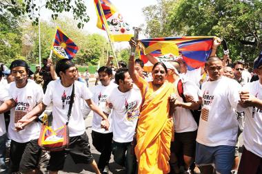 Indijska političarka Jaya Jaitley z visoko dvignjeno baterijsko svetilko, ki je na demonstracijah v New Delhiju nadomeščala prepovedano »plamenico svobode«, obkrožena z živim ščitom najbolj mišičastih med Tibetanci.