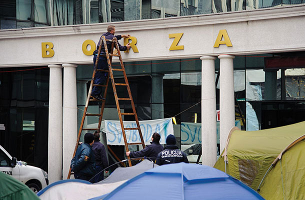 Foto tedna Nazaj h kapitalizmu - namesto »boj za« je borza spet samo »borza« (na sliki nameščanje odpadle črke R in odstranitev črke J v napisu na stavbi ljubljanske borze)