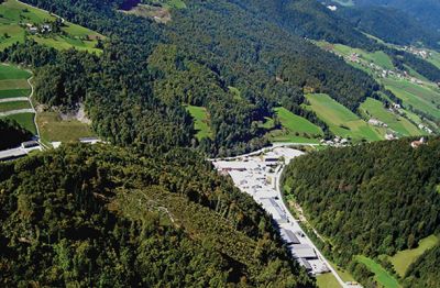 Pogled na območje zaprtega rudnika urana Žirovski vrh iz zraka. Na trikotnem zemljišču v sredini so včasih stali predelovalni objekti rudnika. Danes je tam gospodarska cona.   Levo zgoraj je sanirano odlagališče rudarske jalovine Jazbec. Glavni vhod v rudnik je bil prav pod vrhom na zeleni površini. Vhod je sedaj zabetoniran in beton je prekrit in zatravljen. Zasuti in zabetonirani so tudi vsi vertikalni zračilni jaški. Direktor rudnika Peter Dolenc dvomi, da bi bilo vnovično odprtje izvedljivo.