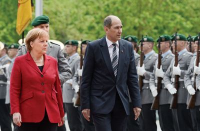 Angela Merkel in Janez Janša pred častno četo nemške vojske, 9. maja 2012 v Berlinu. (Pohvalno pa je, da ima naš Janez dlani, v nasprotju z Angelo, strumno pokrčene ob nogah, tako kot so ga naučili v JLA.)