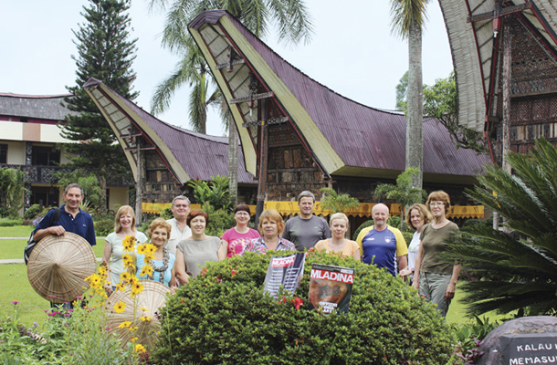 Kiro, Mira, Nevenka, Tomo, Sandra, Maja, Marija, Janez, Maja, Stojan, Nina in Majda pred hišami z dimom – Tongkonan, Indonezija / Foto Mira Gorenšek