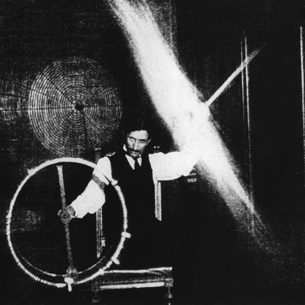 Nikola Tesla izvaja spektakularen prikaz elektrike. Skozi svoje telo je spustil elektriko visoke napetosti, ki jo je ustvaril s tuljavo, ki se odziva na valove iz oddaljenega oscilatorja.