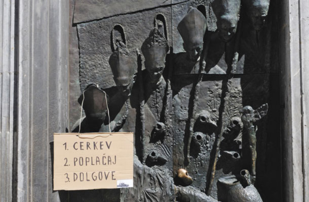 Tri teze Odbora za pravično in solidarno družbo na vratih ljubljanske stolnice. Na njih je upodobljena zgodovina ljubljanske nadškofije, posredno tudi katoliške cerkve na Slovenskem. Predstavniki Odbora so prepričani, da bi morala cerkev iz svojih nepremičnin in drugega premoženja poplačati upnike. 