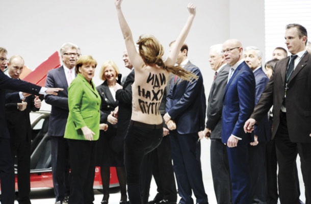 Zadovoljen Vladimir Putin in presenečena Angela Merkel na protestni akciji Femen proti diktatorju na otvoritvi industrijskega sejma v Hannovru.