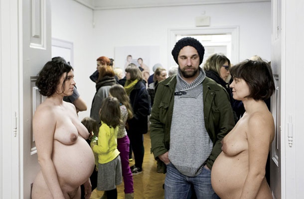 Fotografija otvoritvenega performansa, ko je Janša med vrata postavil gole nosečnice.