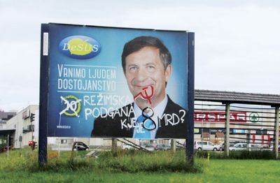  Desus: na Erjavca so se spravili z vsemi topovi – zmerjajo ga z »režimsko podgano« in sprašujejo, »kje je 8 mrd?«, poleg tega sta srp in kladivo obvezen dekor na večini plakatov; intervencija je v razkošnih treh barvah, tole je edini plakat, na katerem so črke naslikane s čopičem, ne pa s klasičnim sprejem. (Križišče proti Čirčam)