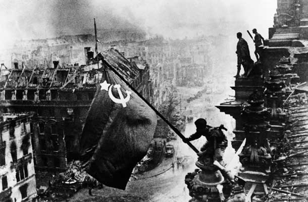 Osvoboditelji Berlina: Vojak Rdeče armade z zastavo na strehi Reichstaga v Berlinu 1. maja 1945 