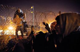 Obupani migranti poskušajo preplezati ograjo v Calaisu, da bi prišli do tovornjakov, ki skozi tunel pod Rokavskim prelivom peljejo do Velike Britanije.  
