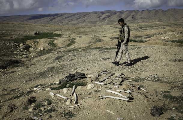 Kurdski borec nad množičnim grobiščem Jezidov, ki so ga zagrešili borci Islamske države pri mestu Sinjar v Iraku, november 2015