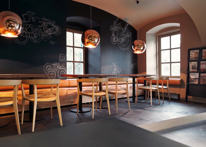 Na vogalu območja, kjer je stala nekdanja tovarna koles, je biro AKSL načrtoval ureditev novega lokala. Črne stene in tla so kombinirani z lesenimi mizami in stoli, nekaterimi lesenimi stenami ter nekaj nenavadnimi poudarki. Najbolj izstopajoče so velike, bakreno barvane luči nad mizami. Skupen učinek bi zaradi črnine in bakra lahko bil morbiden, a je prav nasprotno – prostor je presenetljivo udoben in domač, pretirano resnobnost pa razbijejo risbice koles na stenah.