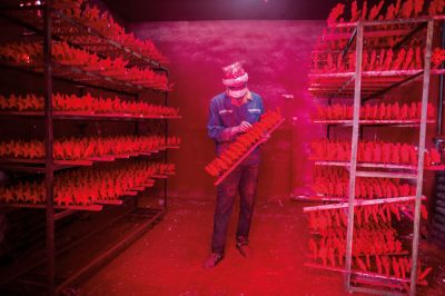 Delavec v rdečem prahu v tovarni božičnih okraskov v kitajskem mestu Yiwu