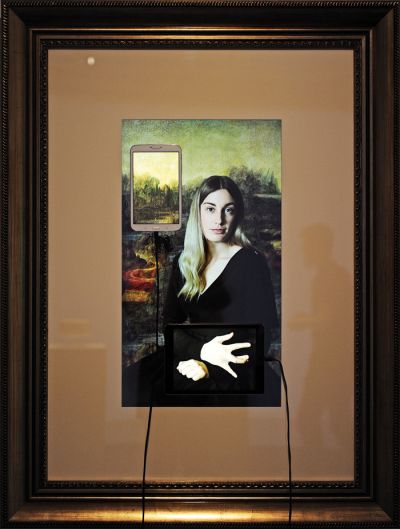Avtoportretna reinterpretacija Mona Lise: obiskovalci ljubljanske galerije Aksioma lahko na tabličnem računalniku in pametnem telefonu spreminjajo pozicijo njenih rok, tem premikom pa sledi tudi smer njenega pogleda. 