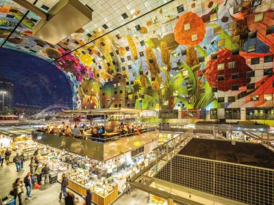 Markthal, Rotterdam. Ogromno tržno dvorano s strani zaobjameta stavbna trakta, ki imata v prerezu obliko podkve. V notranjosti prodajne paviljone dopolnjujejo gostinski lokali s terasami na strehah.