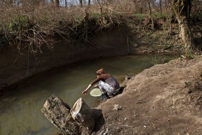 Hčerka Dunje Kočevar med zajemanjem »pitne« vode iz bližnjega potoka 