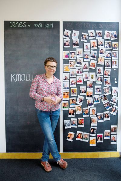 Karolina pred panojem s fotografijami bivših in sedanjih sodelavcev Centra alternativne in avtonomne produkcije