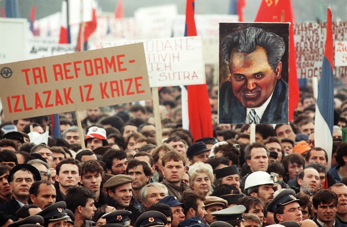 Miting na Ušću, konec leta 1988. Prišlo naj bi milijon ljudi, množica je skandirala proti Sloveniji, proti Milanu Kučanu, proti Janezu Stanovniku, zahtevala je veliko Srbijo. Boscarol je tem ljudem prodajal priponke.