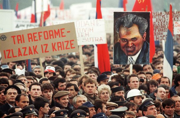 Miting na Ušću, konec leta 1988. Prišlo naj bi milijon ljudi, množica je skandirala proti Sloveniji, proti Milanu Kučanu, proti Janezu Stanovniku, zahtevala je veliko Srbijo. Boscarol je tem ljudem prodajal priponke.