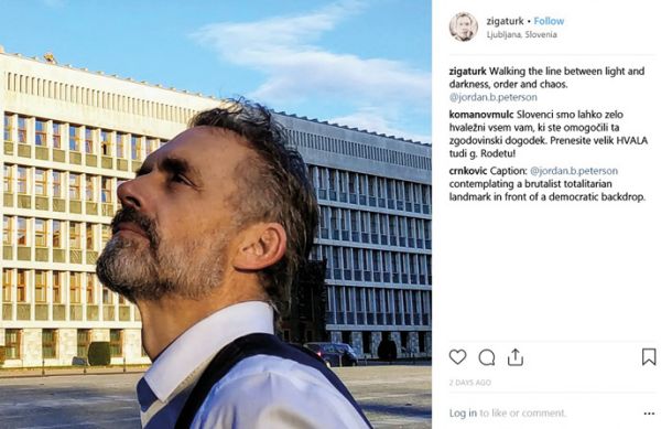 Fotografija Jordana Petersona pred polovično osvetljenim slovenskim parlamentom. Avtor fotografije, Žiga Turk, je fotografijo opremil s podpisom o »hoji med svetlobo in temo, redom in kaosom«.