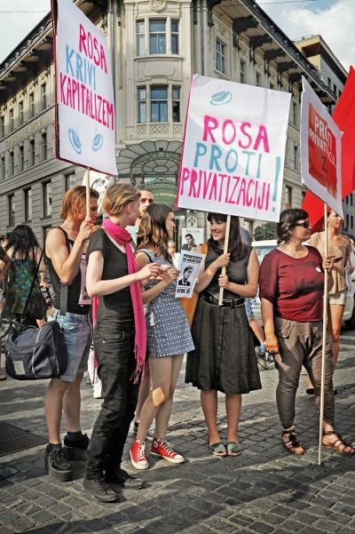 Nika Kovač, sociologinja, direktorica Inštituta 8. marec in aktivistka na protestih proti privatizaciji leta 2015 (na fotografiji s transparentom v rokah). 