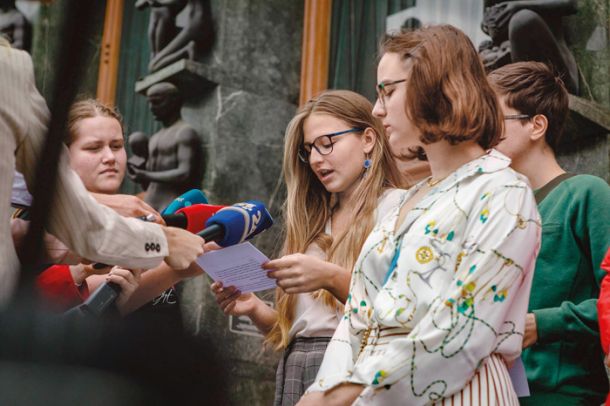 Tija Jakič z Inštituta 8. marec pred parlamentom prebira poziv proti odpravi dodatka za delovno aktivnost 