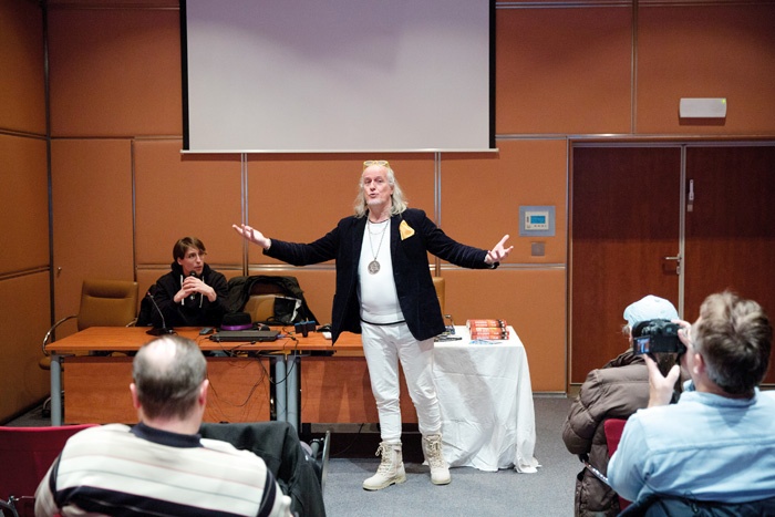 Predavateljski kateder je zavzel Ezael, glavni predstavnik slovenske raeljanske skupnosti. Okoli vratu je nosil medaljon, na katerem sta hkrati žarela svastika in Davidova zvezda.