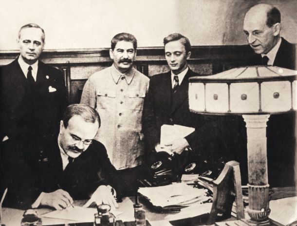 Sovjetski zunanji minister Vjačeslav Molotov pod Stalinovim budnim očesom podpisuje sporazum s Hitlerjevo Nemčijo. Na Stalinovi desni je nemški zunanji minister Ribbentrop.