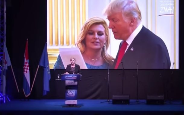 Kolinda na govorniškem odru, zadaj na zaslonu pa na fotografiji z ameriškim predsednikom Donaldom Trumpom