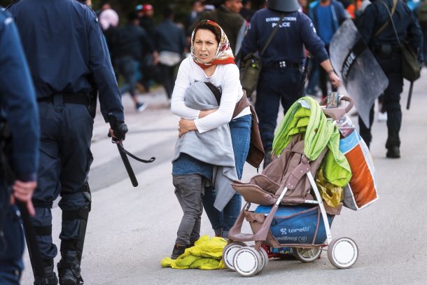 Mati z otrokom na otoku Lezbos med posredovanjem policije. Slednja namreč beguncem preprečuje vkrcanje na ladje, ki odrinejo proti celinski Grčiji. 3. marec 2020 