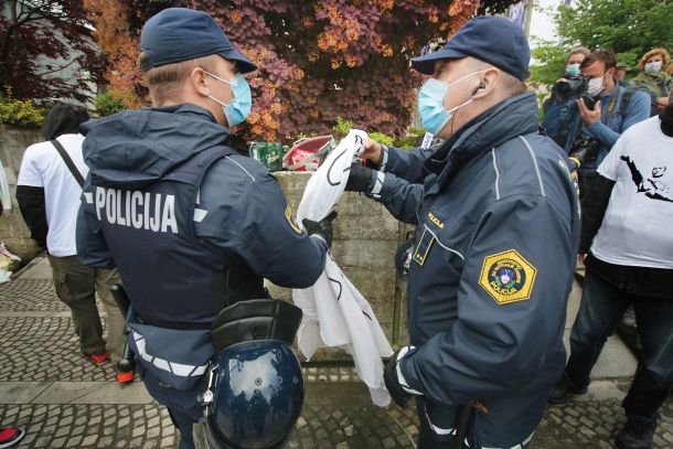 Žaljivi transparent o smrti in janšizmu, ki so ga na protestu zasegli policisti