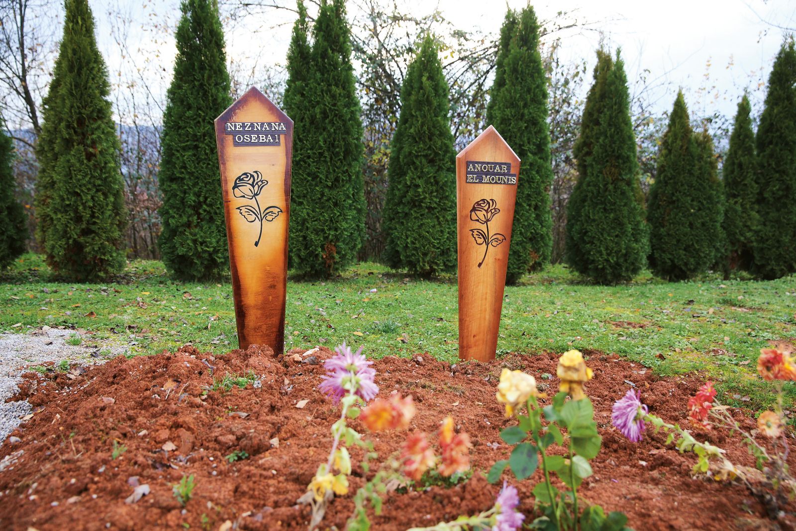 Grobova migrantov, ki sta utonila v reki Kolpi pri poskusu prečkanja meje, na kateri slovenski policisti tujcem sporočajo, da v Sloveniji „ni azila“. Pokopališče Vojna vas v Črnomlju.